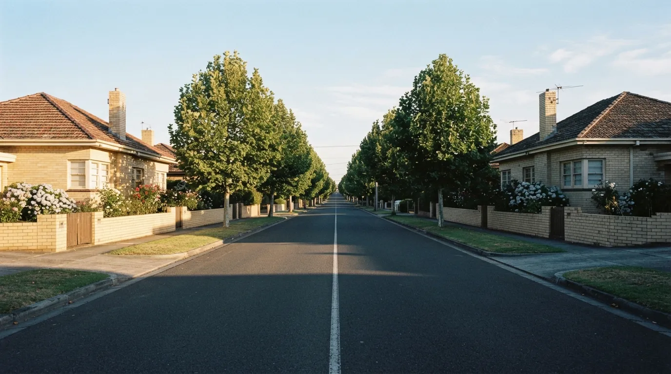 An elevated view along a street of brick homes in Melbourne's south-east with a school and oval visible two blocks away
